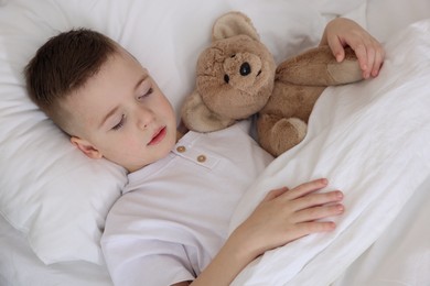 Photo of Bedtime. Cute boy sleeping with his teddy bear in bed