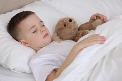 Bedtime. Cute boy sleeping with his teddy bear in bed