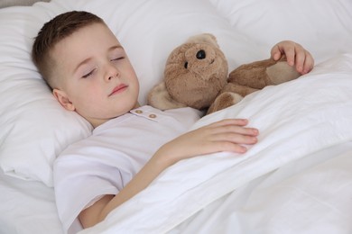 Bedtime. Cute boy sleeping with his teddy bear in bed