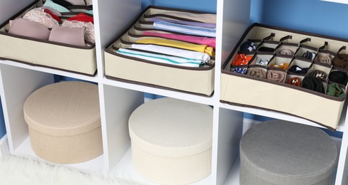 Photo of Organizers with folded clothes and underwear on shelves at home