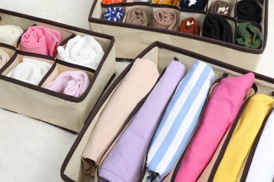 Photo of Organizers with folded clothes on carpet indoors, closeup