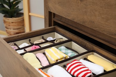 Photo of Organizers with folded clothes in drawer indoors, closeup