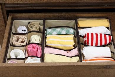 Photo of Organizers with folded clothes in drawer indoors, closeup