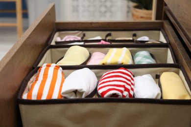 Photo of Organizers with folded clothes in drawer indoors, closeup