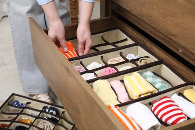 Woman putting sock into organizer in drawer at home, closeup