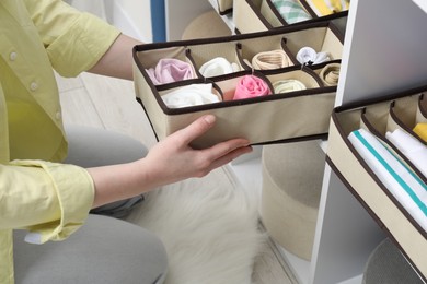 Photo of Woman putting organizer with different socks onto shelf at home, closeup