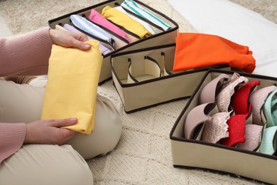 Woman organizing clothes on bed at home, closeup