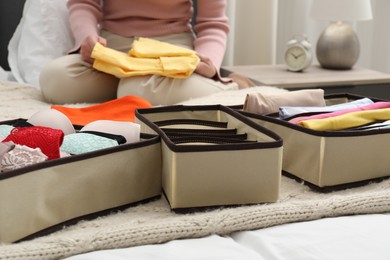 Photo of Woman organizing clothes on bed at home, closeup