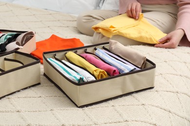 Woman organizing clothes on bed at home, closeup