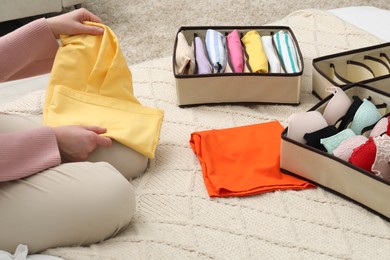 Woman organizing clothes on bed at home, closeup