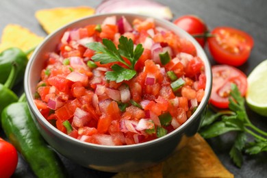 Delicious salsa in bowl and ingredients on grey table, closeup