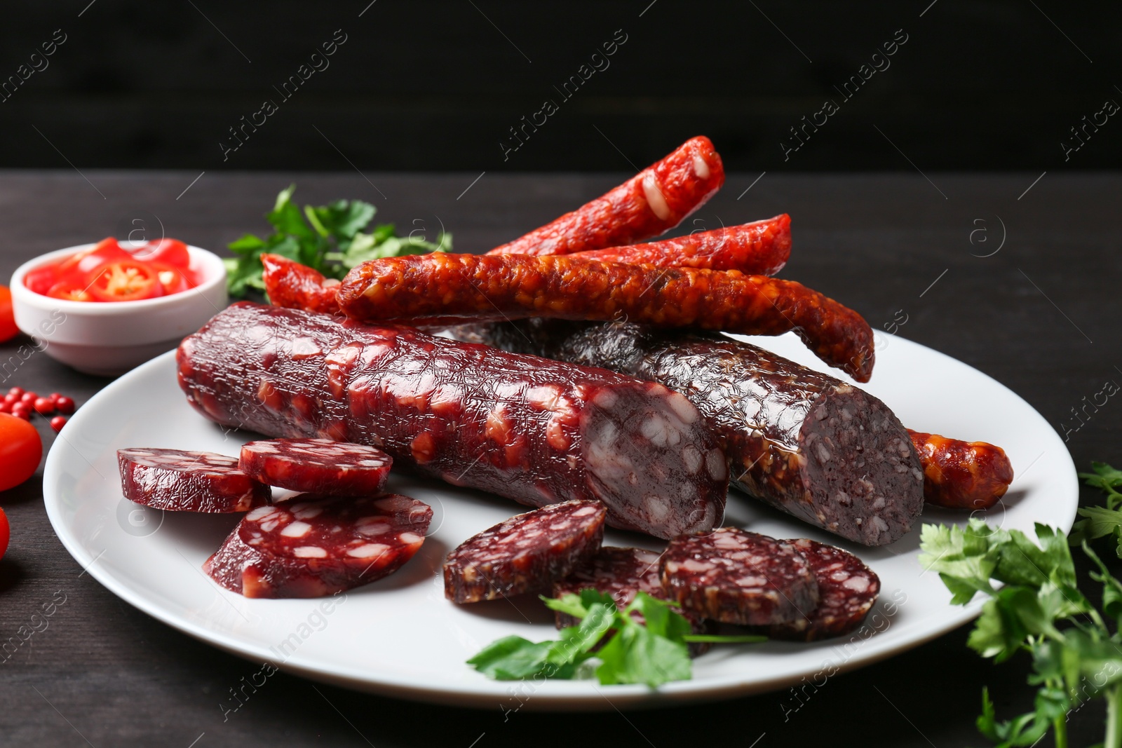 Different smoked sausages and spices on dark wooden table, closeup Photo of Different smoked sausages and spices on dark wooden table, closeup