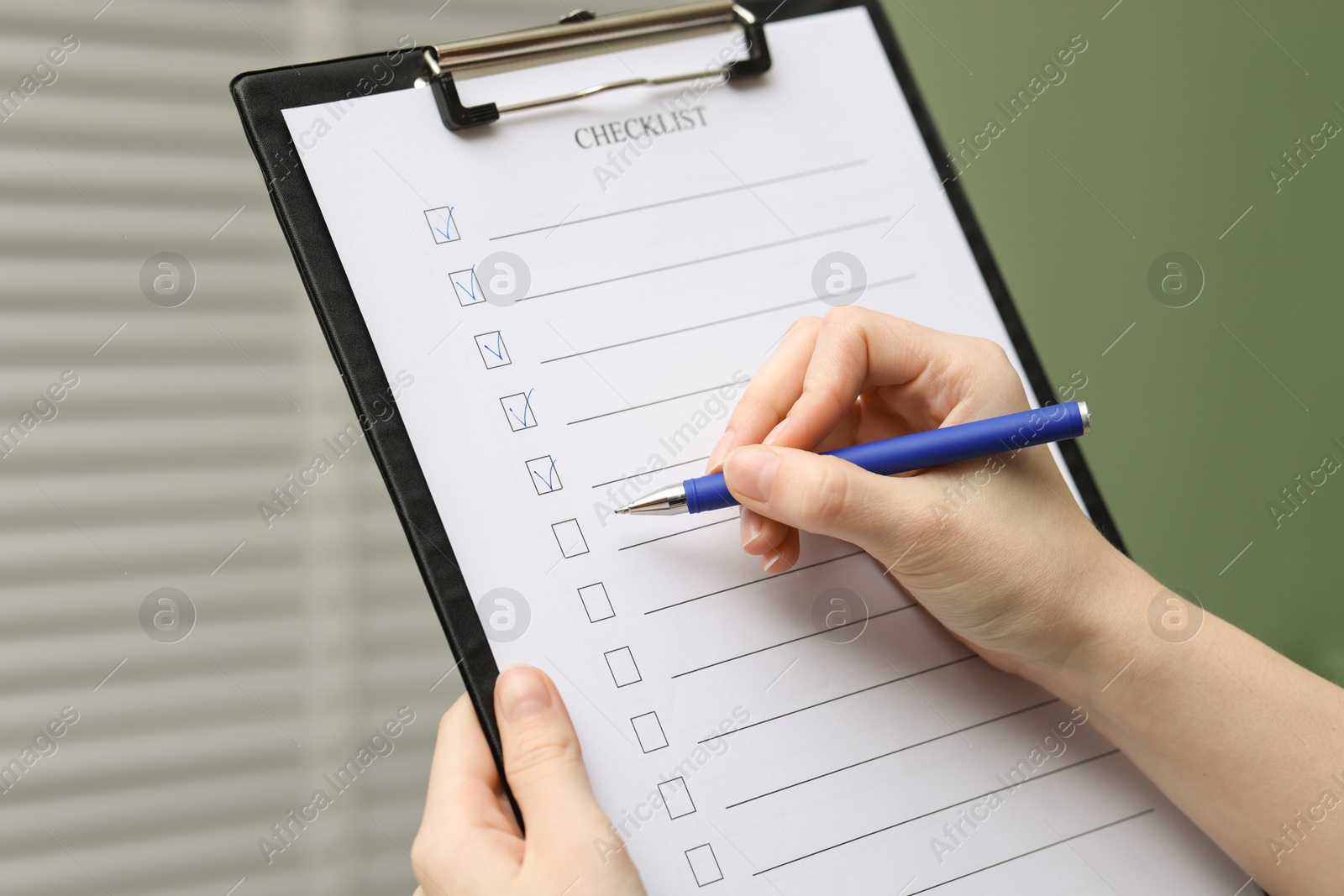 Photo of Woman filling Checklist with pen indoors, closeup