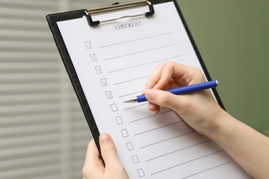 Woman filling Checklist with pen indoors, closeup