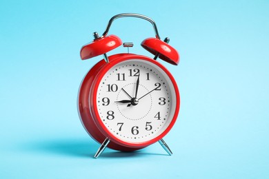 Photo of One red alarm clock on light blue background