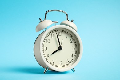 Photo of One white alarm clock on light blue background