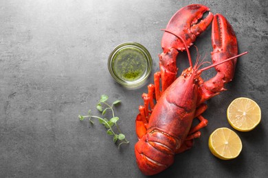 Photo of Delicious boiled lobster with oil, microgreens and lemon pieces on grey table, top view. Space for text