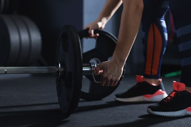 Photo of Sportswoman with barbell during crossfit workout in gym, closeup