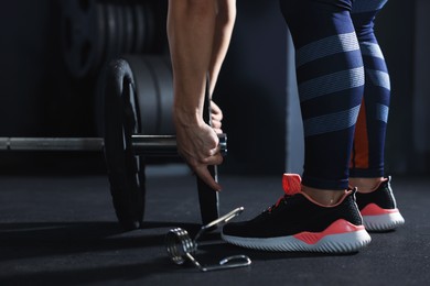 Photo of Sportswoman with barbell during crossfit workout in gym, closeup