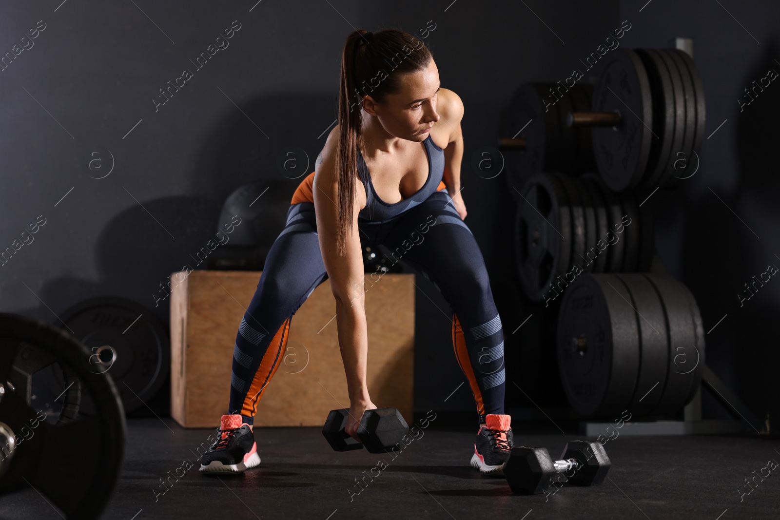 Photo of Sportswoman exercising with dumbbells during crossfit workout in gym