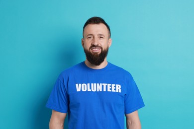 Photo of Positive man wearing t-shirt with word Volunteer on light blue background