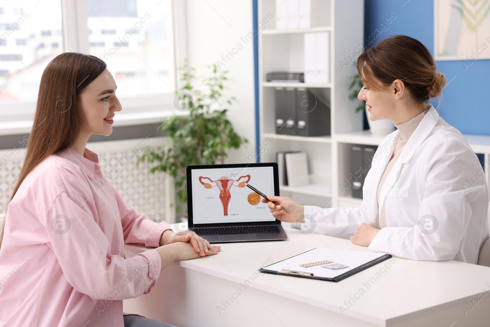 Photo of Contraception. Gynecologist showing image of female reproductive system to woman in clinic