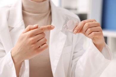 Contraception. Gynecologist recommending condom to woman in clinic, closeup