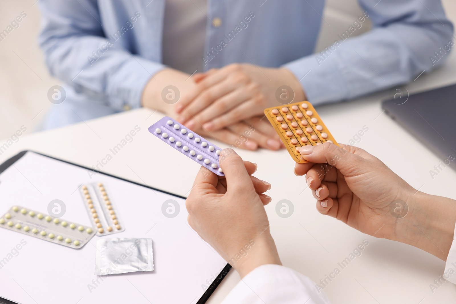 Photo of Gynecologist recommending contraceptive pills to woman in clinic, closeup