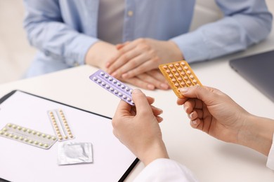 Gynecologist recommending contraceptive pills to woman in clinic, closeup