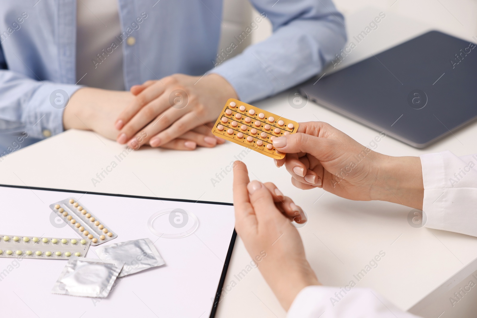 Photo of Gynecologist recommending contraceptive pills to woman in clinic, closeup