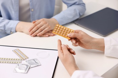 Photo of Gynecologist recommending contraceptive pills to woman in clinic, closeup