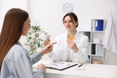 Photo of Gynecologist showing different contraceptive products to woman in clinic