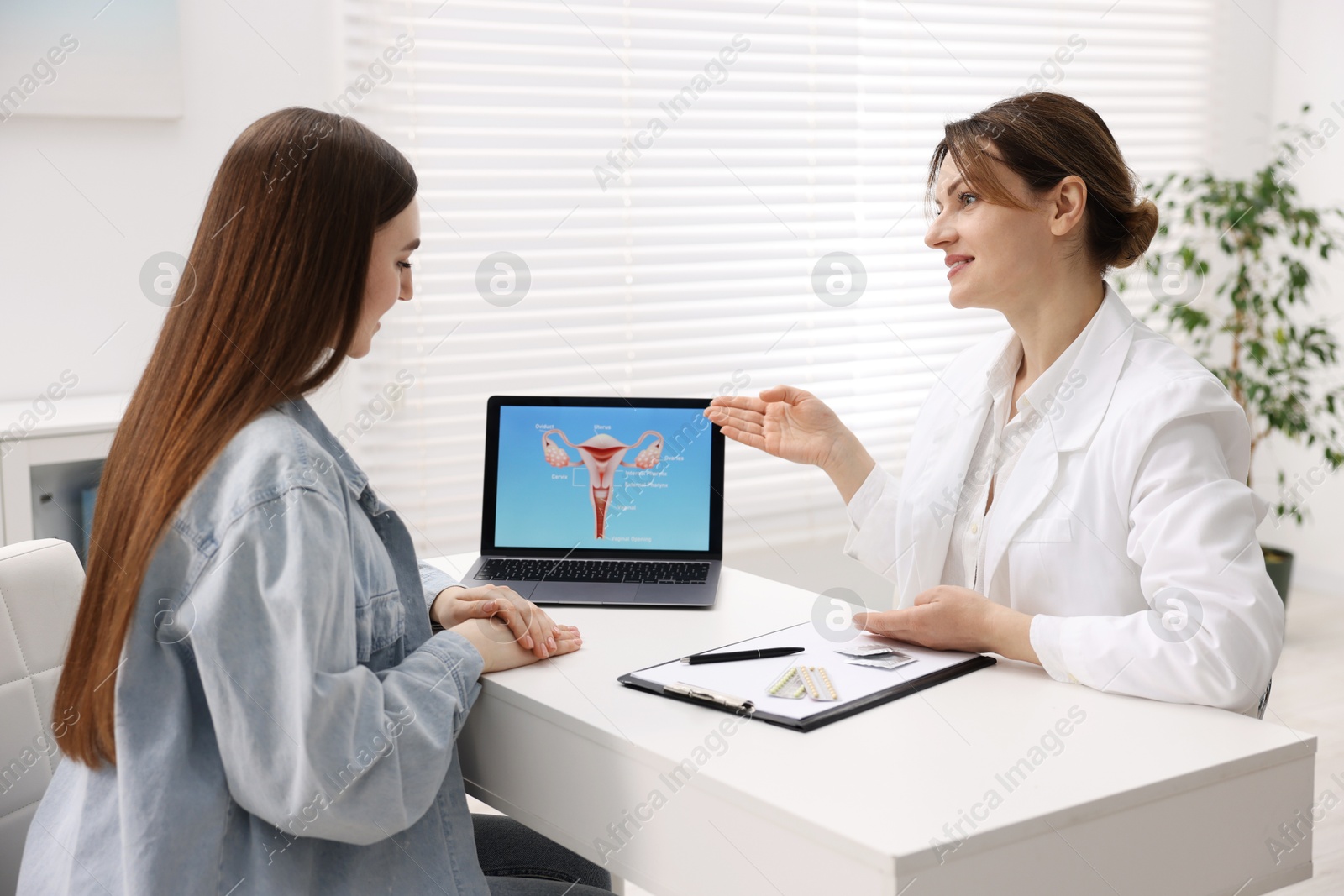 Photo of Contraception. Gynecologist showing image of female reproductive system to woman in clinic