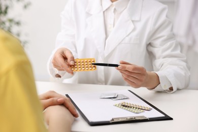 Photo of Gynecologist recommending contraceptive pills to woman in clinic, closeup