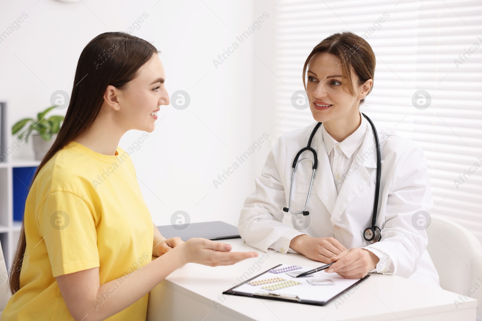 Photo of Gynecologist showing different contraceptive products to woman in clinic