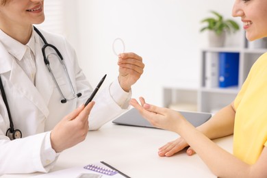 Contraception. Gynecologist recommending vaginal ring to woman in clinic, closeup