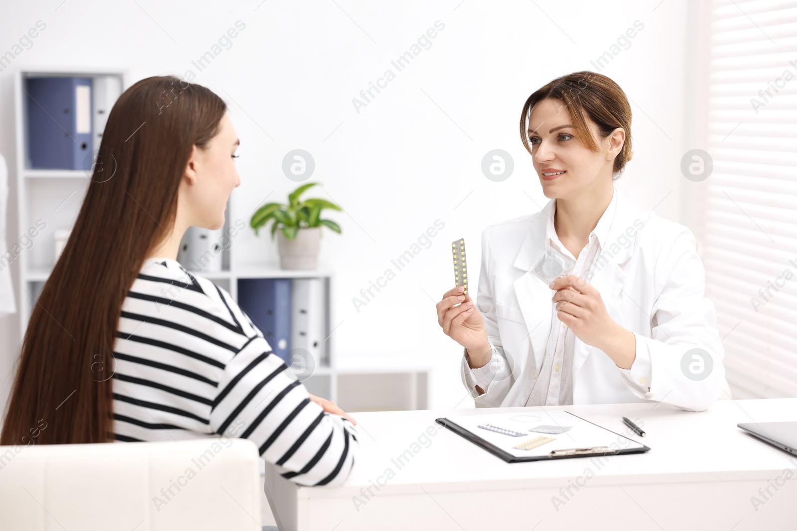 Photo of Gynecologist showing different contraceptive products to woman in clinic