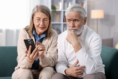 Photo of Cute elderly couple with smartphone on sofa at home