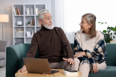 Photo of Cute elderly couple looking at each other on sofa at home