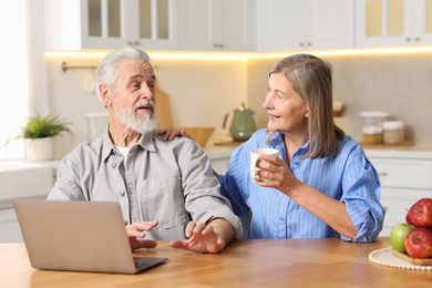 Cute elderly couple spending time together at table in kitchen