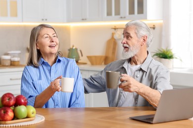 Cute elderly couple laughing at table in kitchen