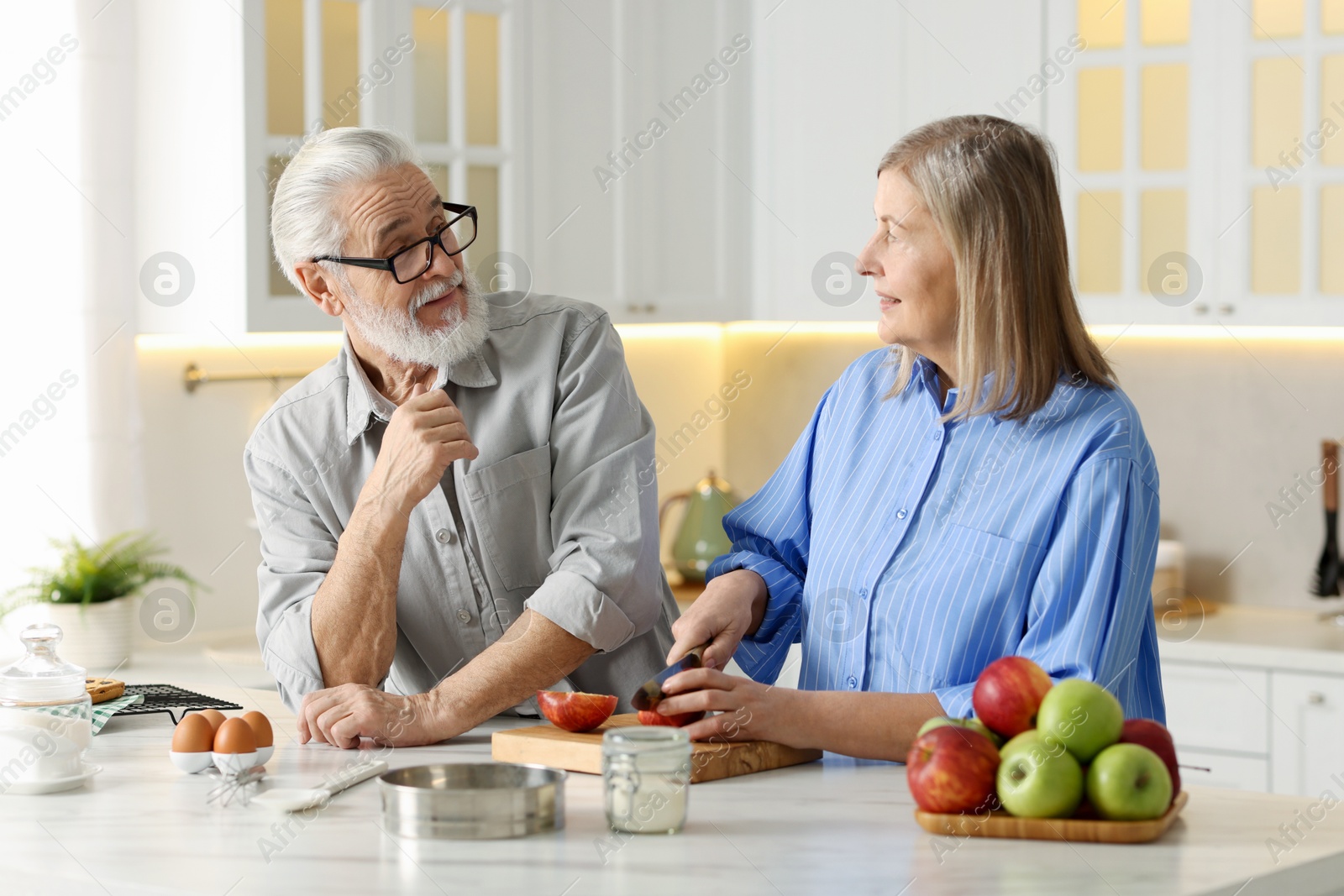 Photo of Cute elderly couple cooking together at table in kitchen