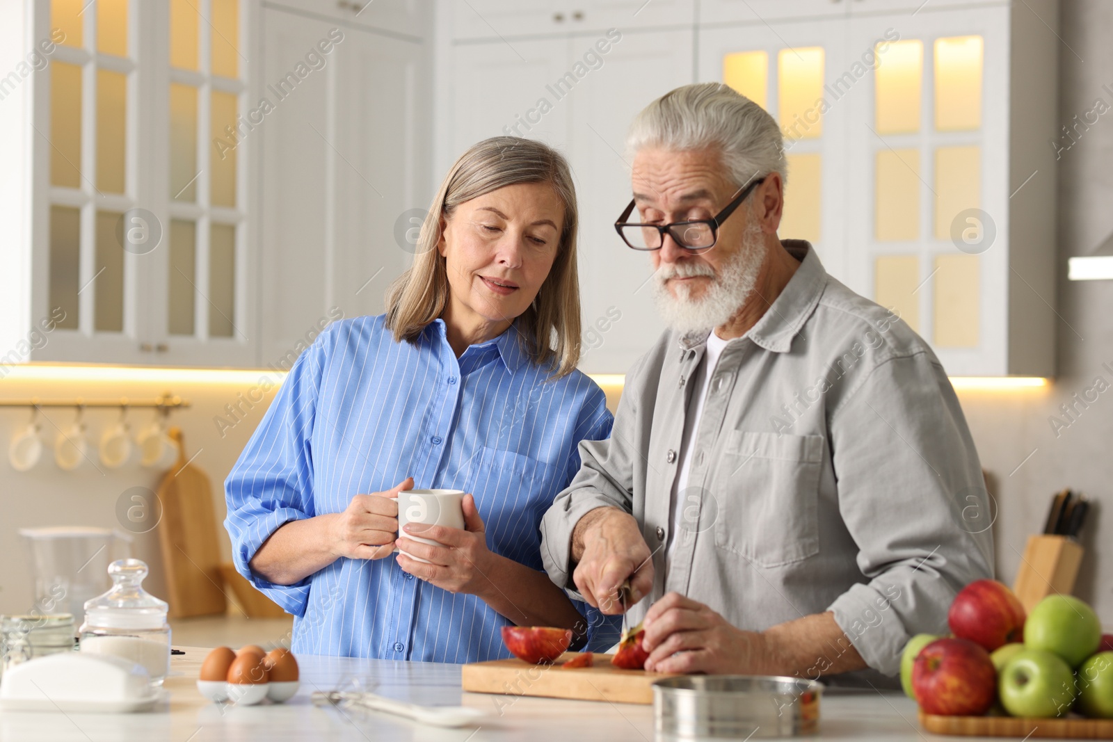 Photo of Cute elderly couple cooking together at table in kitchen