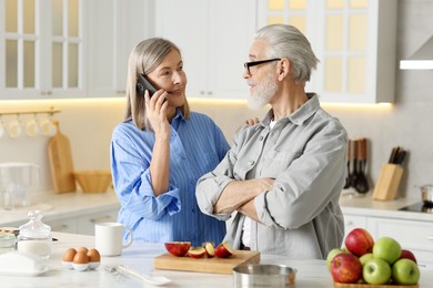 Cute elderly couple spending time together at table in kitchen