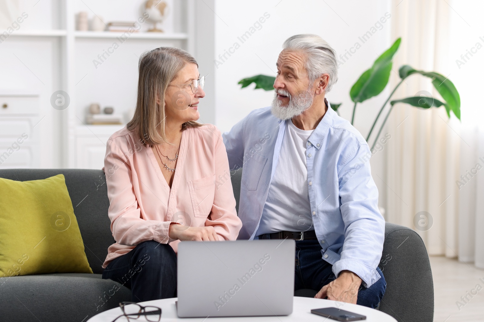 Photo of Happy elderly couple spending time together on sofa at home