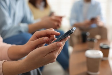 Photo of Internet addiction. Group of people with smartphones and coffee at table indoors, closeup