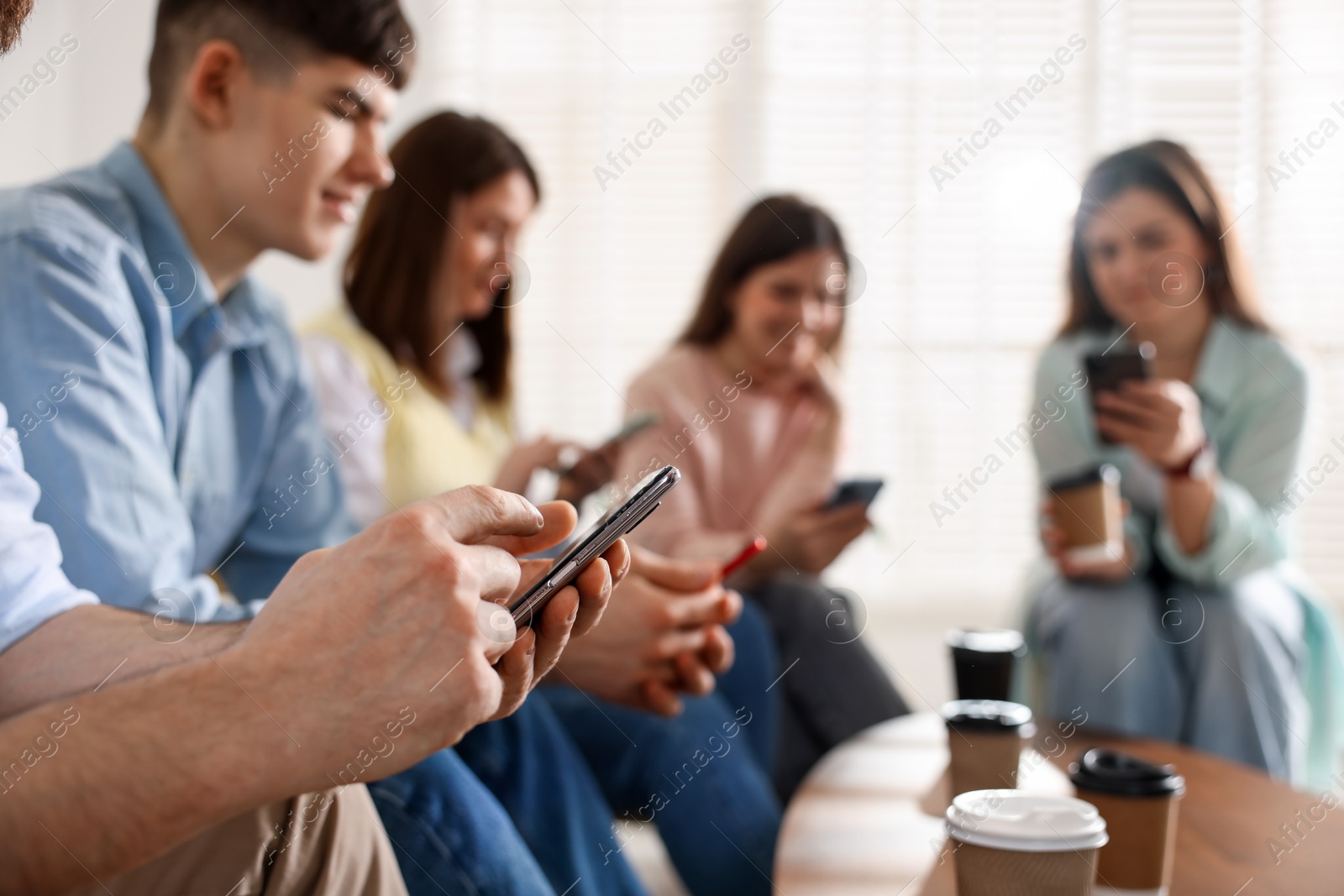 Photo of Internet addiction. Group of people with smartphones and coffee at table indoors, selective focus