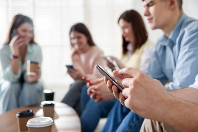 Photo of Internet addiction. Group of people with smartphones and coffee at table indoors, selective focus