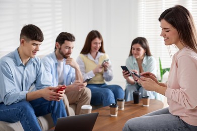 Photo of Internet addiction. Group of friends with gadgets and coffee at table indoors