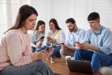 Photo of Internet addiction. Group of friends with gadgets and coffee at table indoors